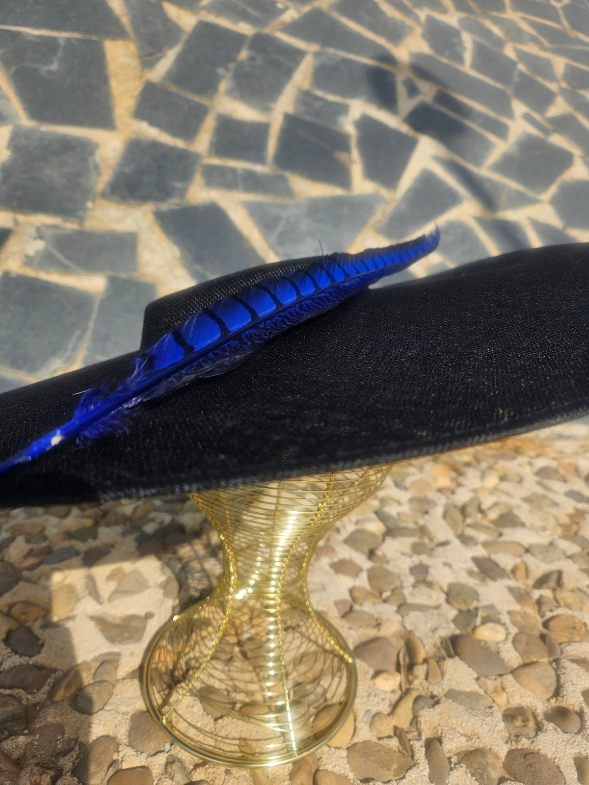 Vista lateral: sombrero negro con cinta azul brillante y pluma decorativa