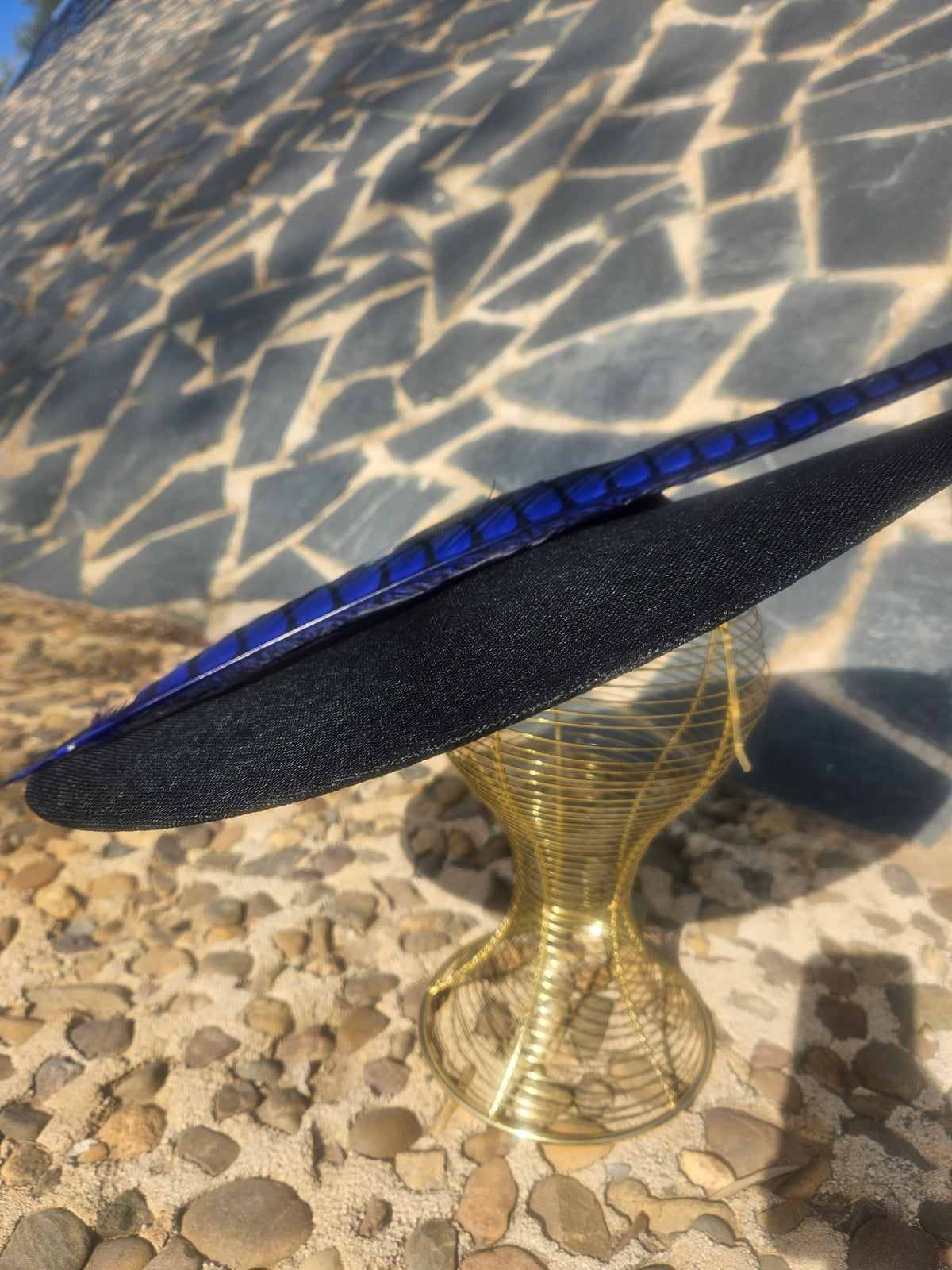 Sombrero negro con cinta azul brillante y pluma larga, tejido fino visible