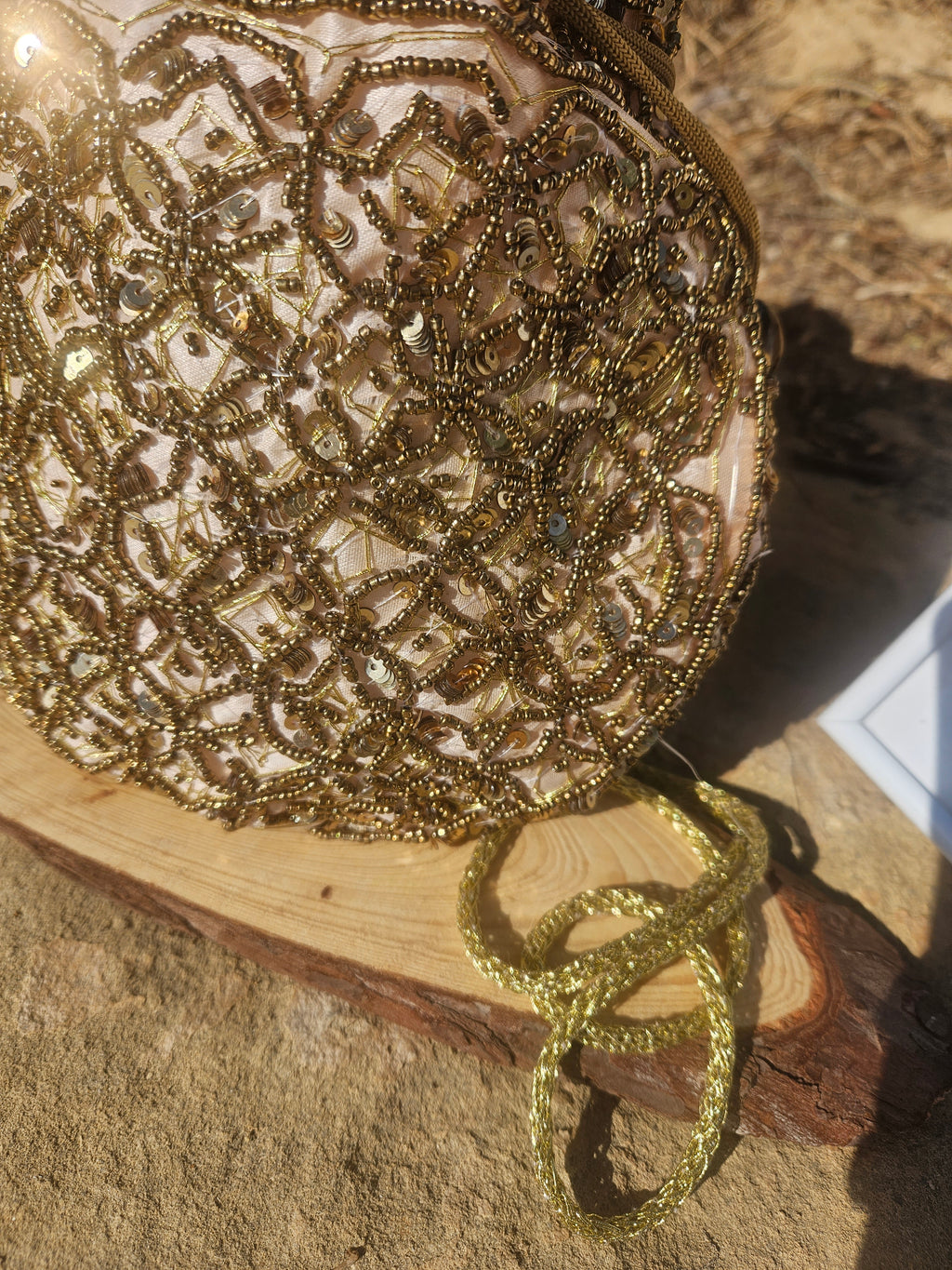 Bolso saco con cuentas brillantes doradas, asa con cordón y cierre superior