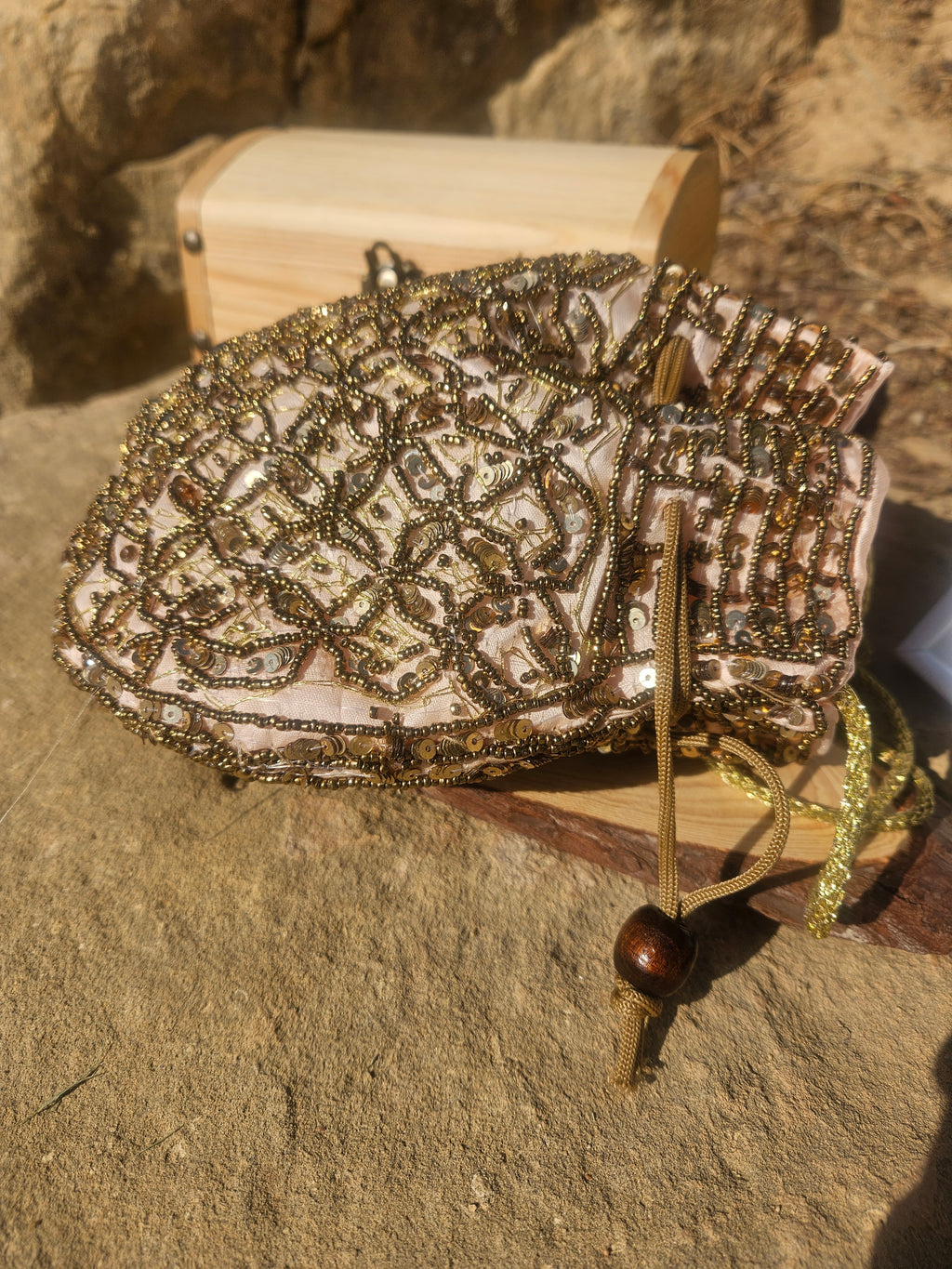 Bolso saco bordado con cuentas doradas, asa de cordón y detalle con borlas