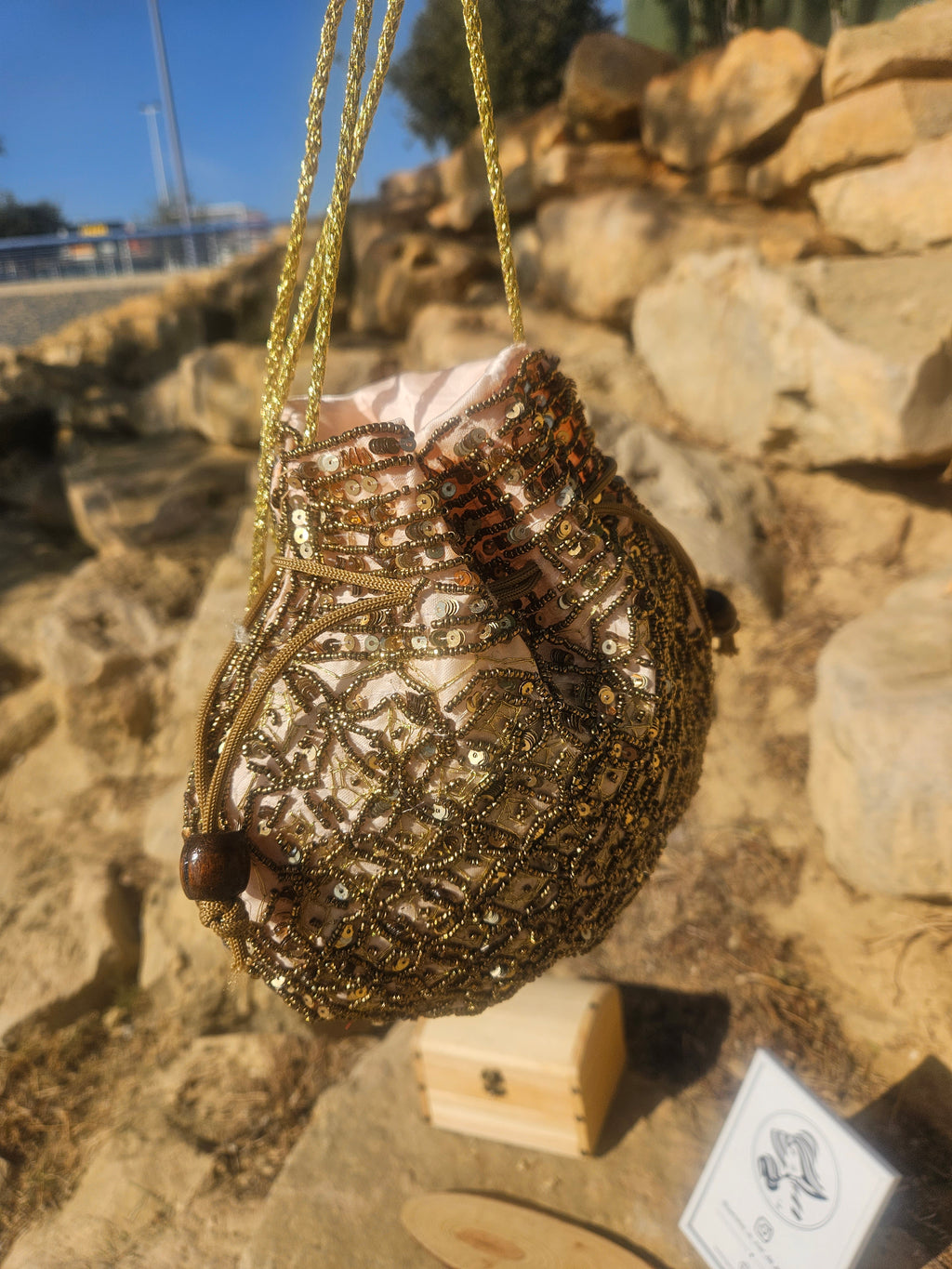 Bolso saco con cuentas doradas y marrones, cordones colgantes y borlas