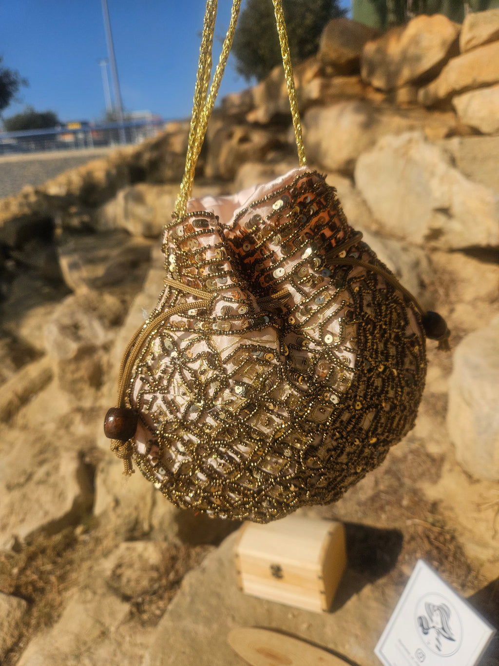 Bolso saco bordado con cuentas doradas, vista frontal con cordones y borlas