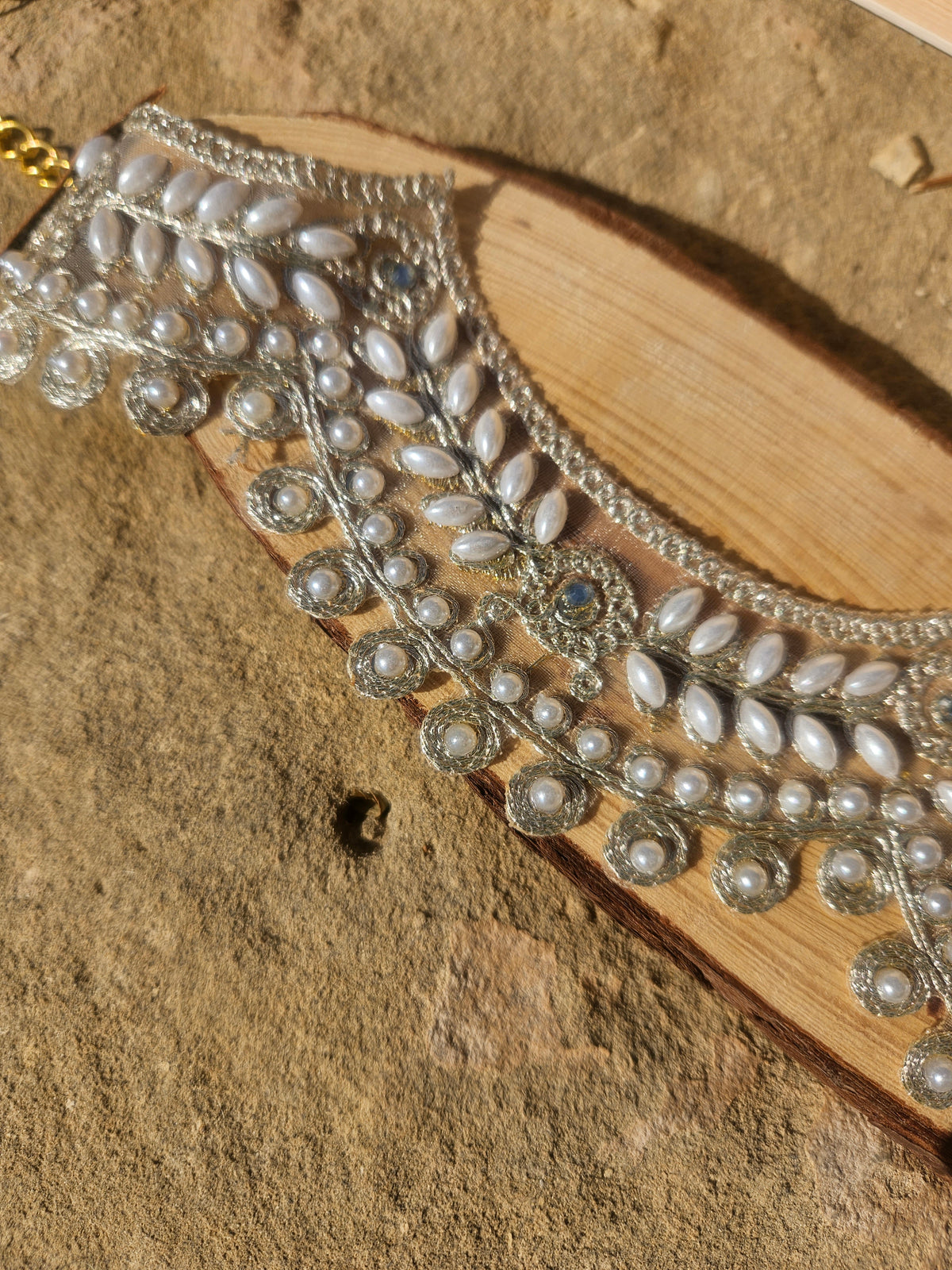 Choker con pedrería y cuentas perla sobre base clara, detalle frontal