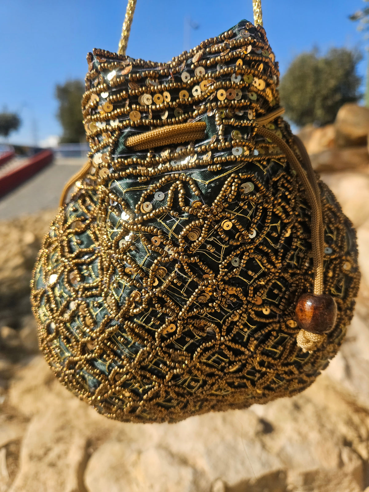 Bolso saco bordado con cuentas turquesa y doradas, detalle de borla y cordones