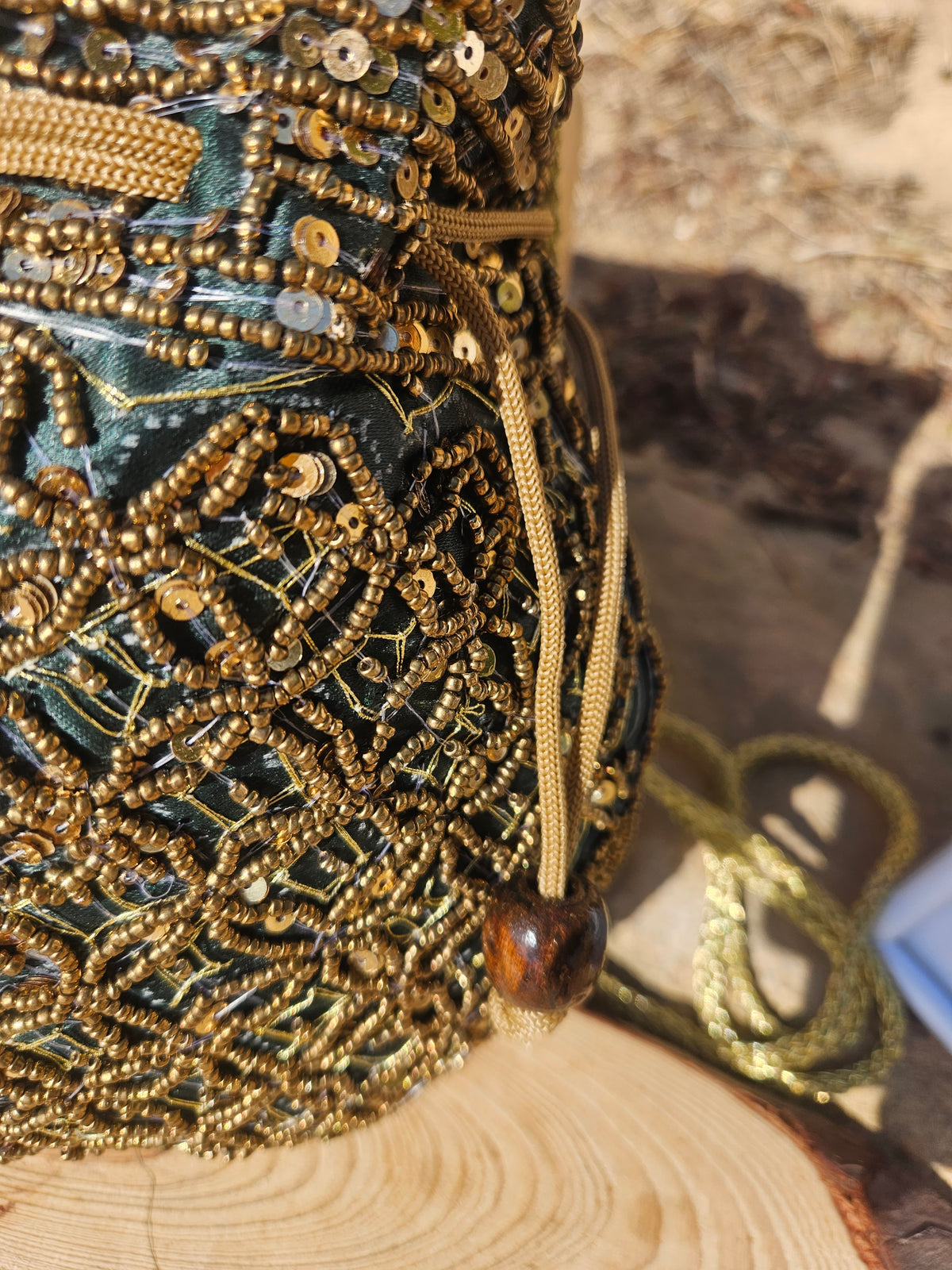 Bolso saco bordado con cuentas turquesa y doradas, cordón lateral y detalle de cuentas