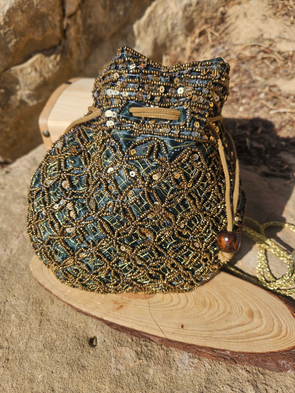 Bolso saco con bordado turquesa y dorado, cordón de cierre y tiras trenzadas