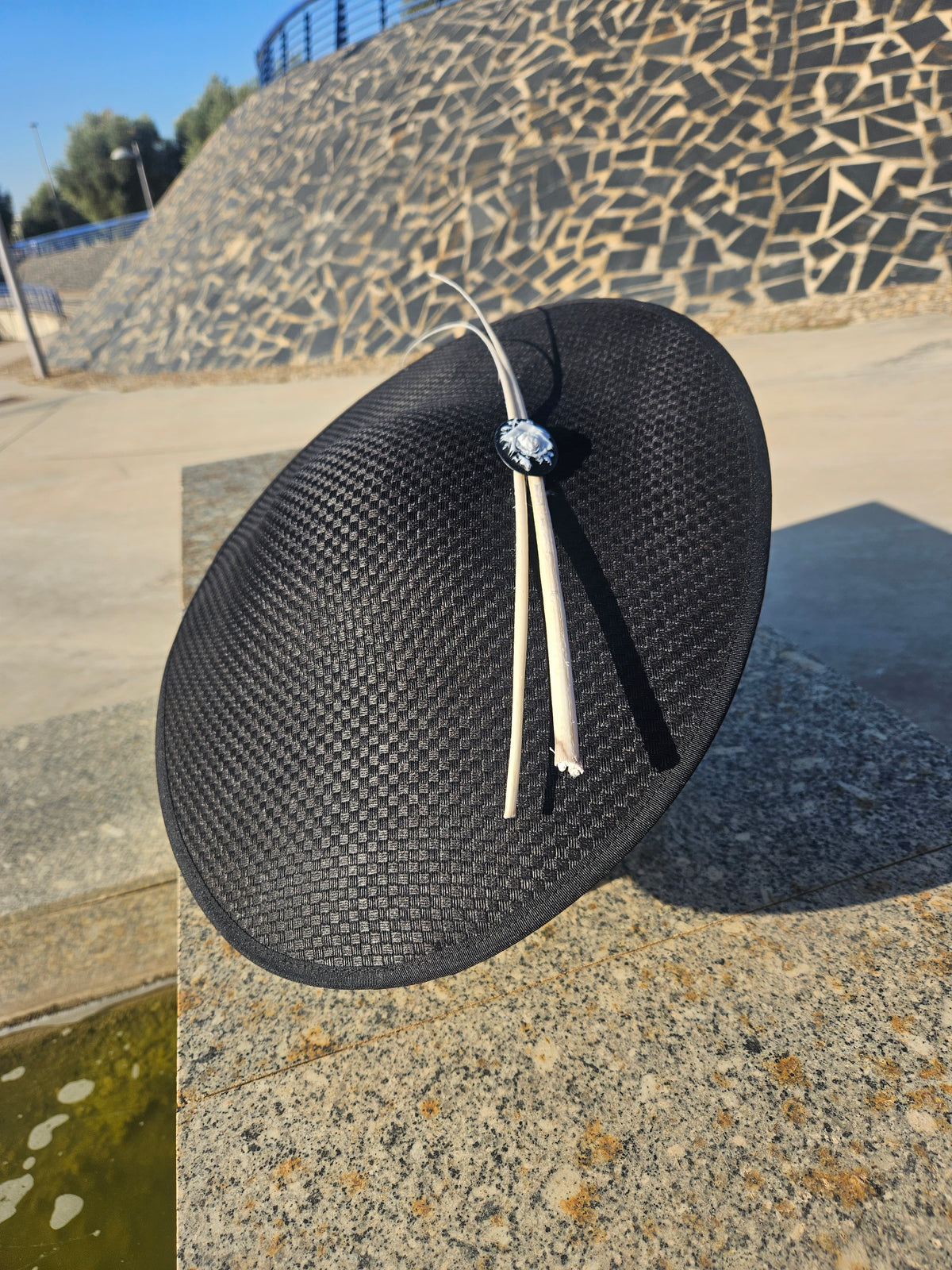 Sombrero pamela negro con cintas colgantes y broche central, ala ancha