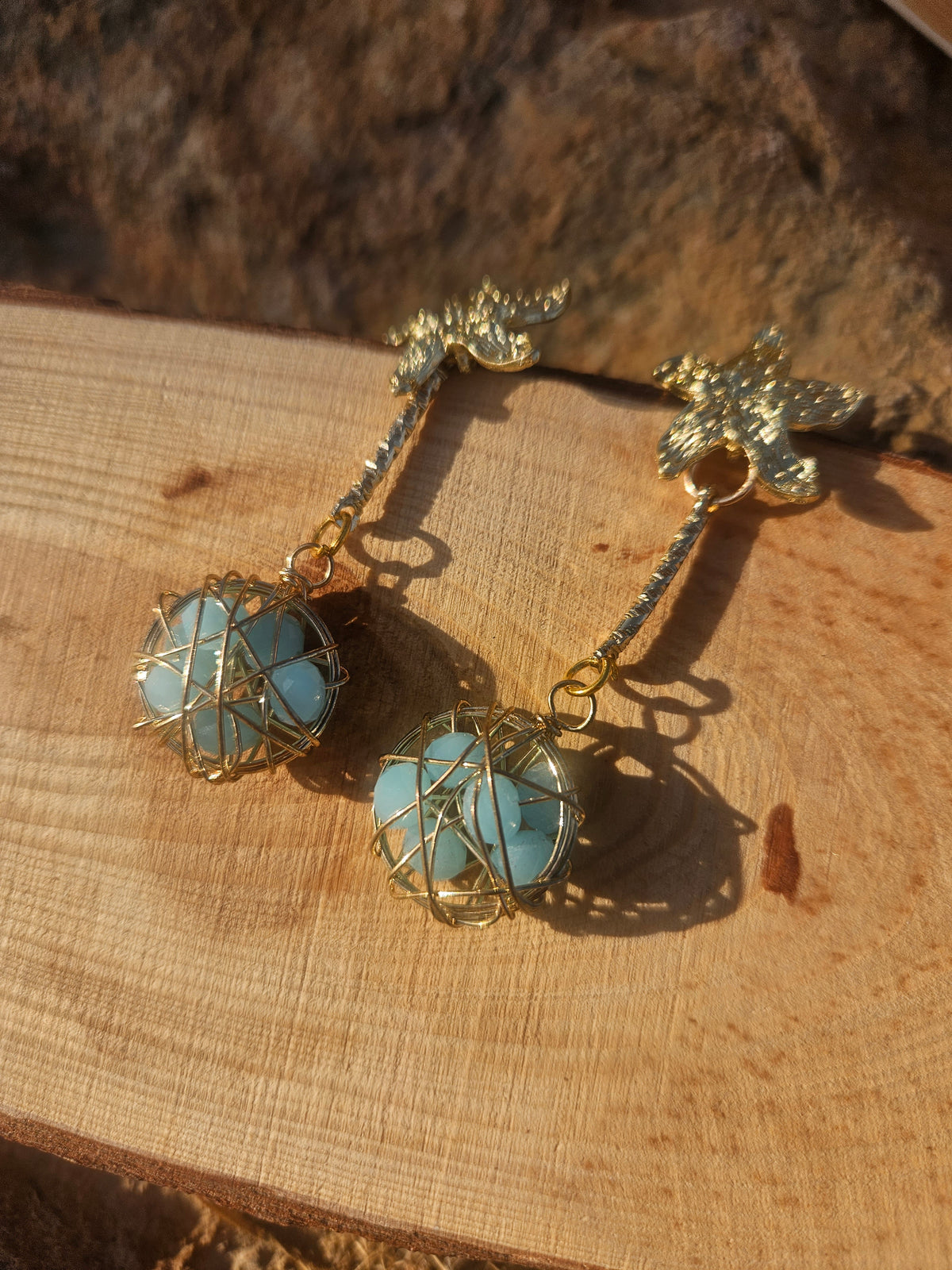 Pendientes Caspio colgantes dorados con dijes florales y esferas azules enrejadas