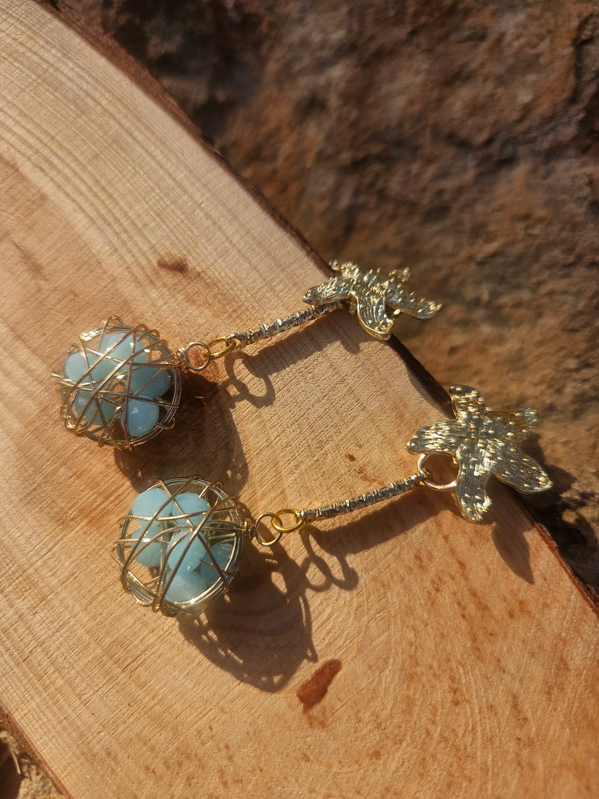 Pendientes Caspio con cadenas doradas y esferas azules enrejadas con dijes florales