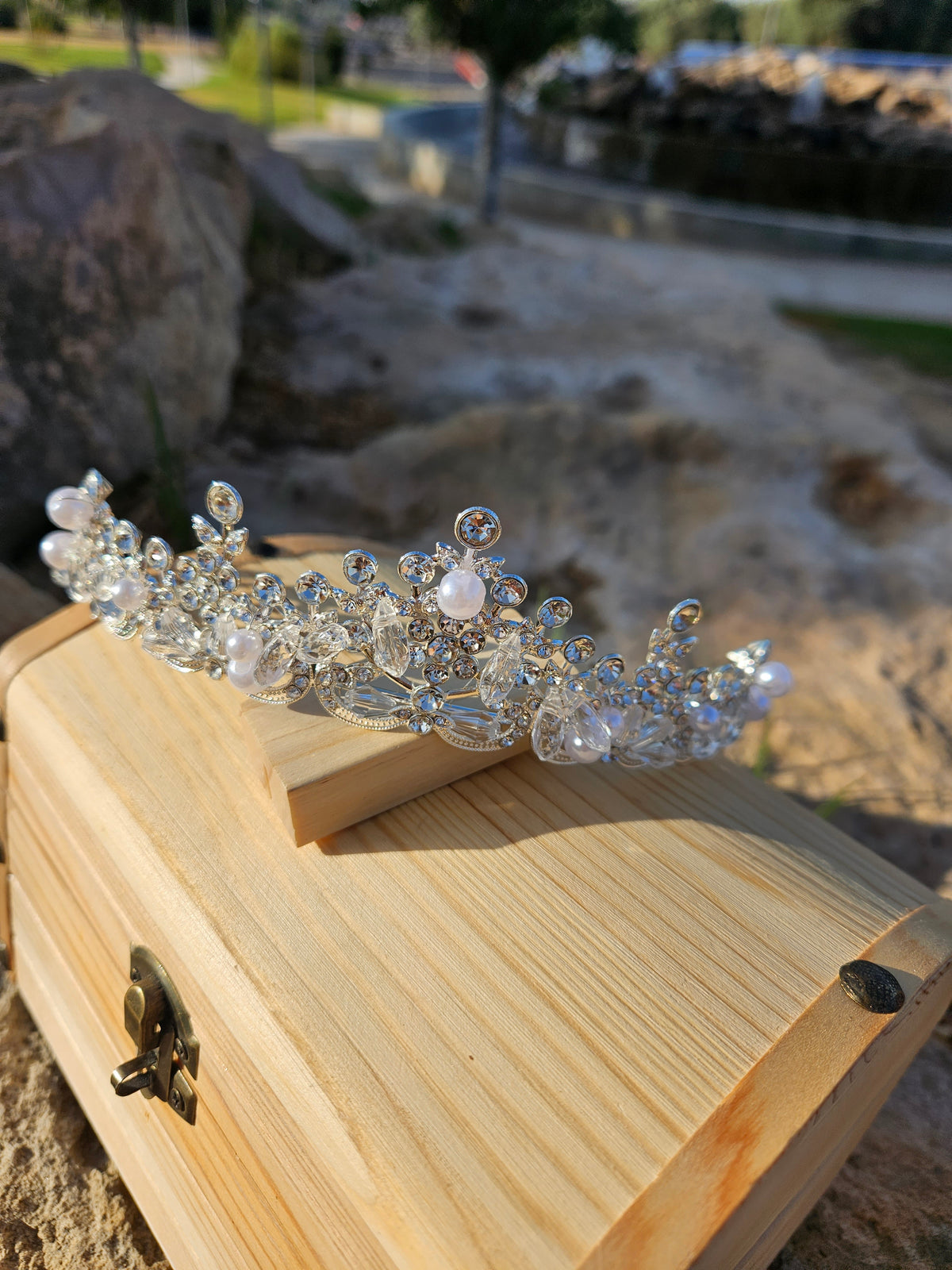 Corona de novia Fátima plateada con pedrería y perlas, sobre base de madera, inclinada