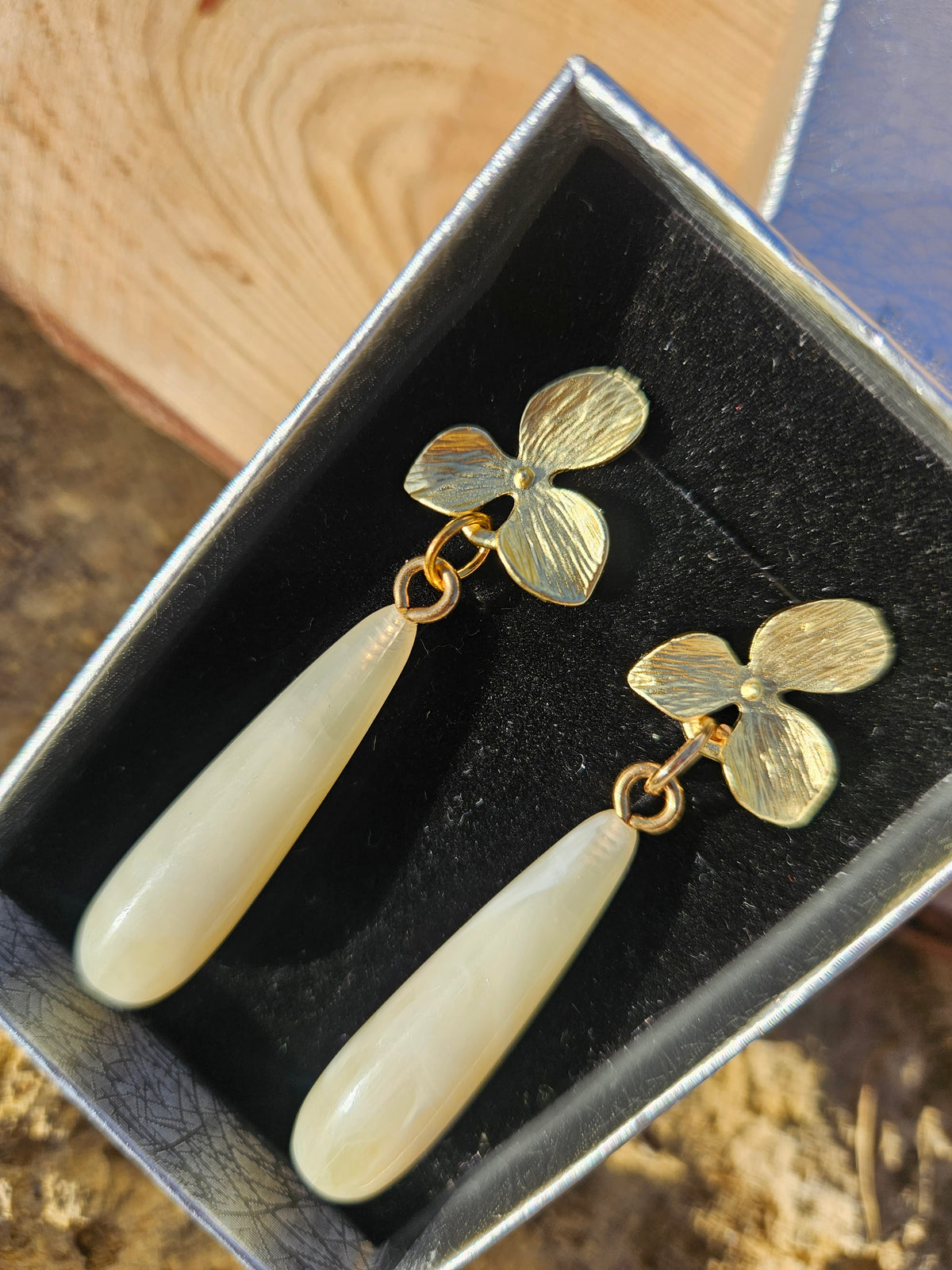 Pendientes con flores doradas y perlas ovaladas marfil, gancho visible