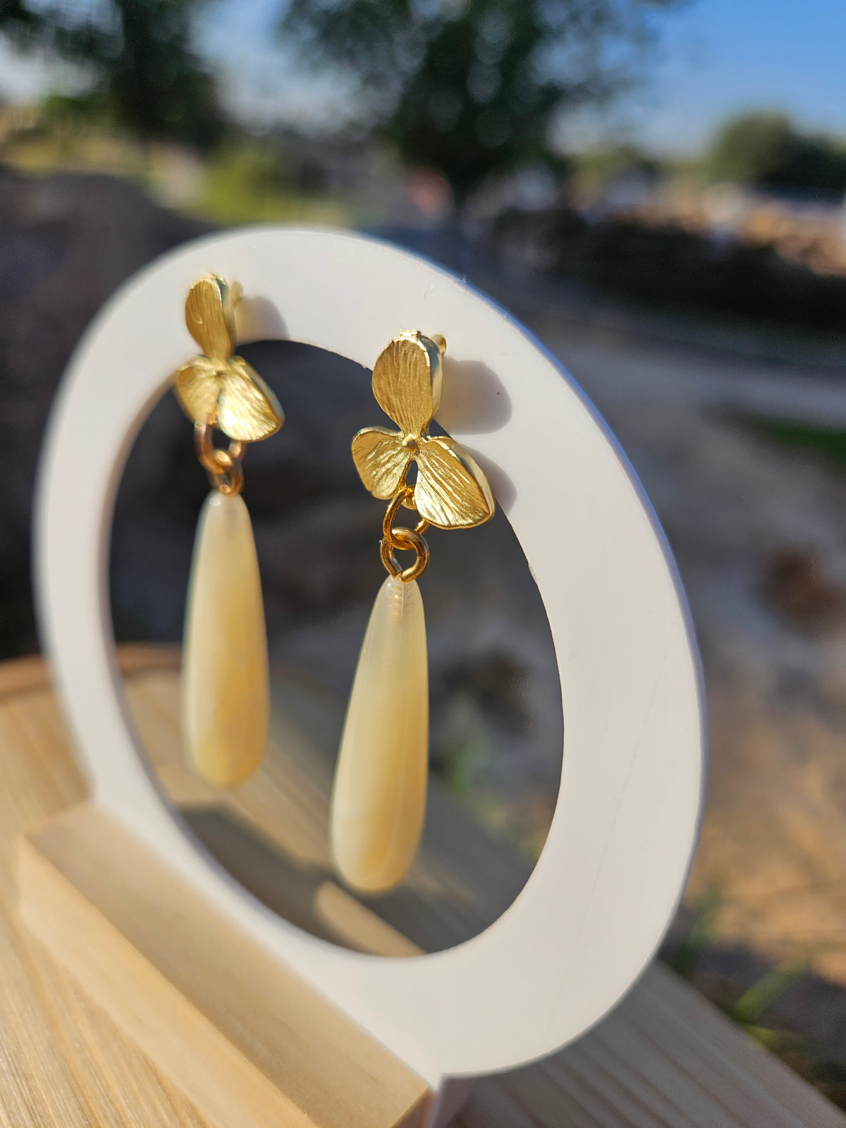 Pendientes colgantes dorados con flor y gota marfil, vista lateral