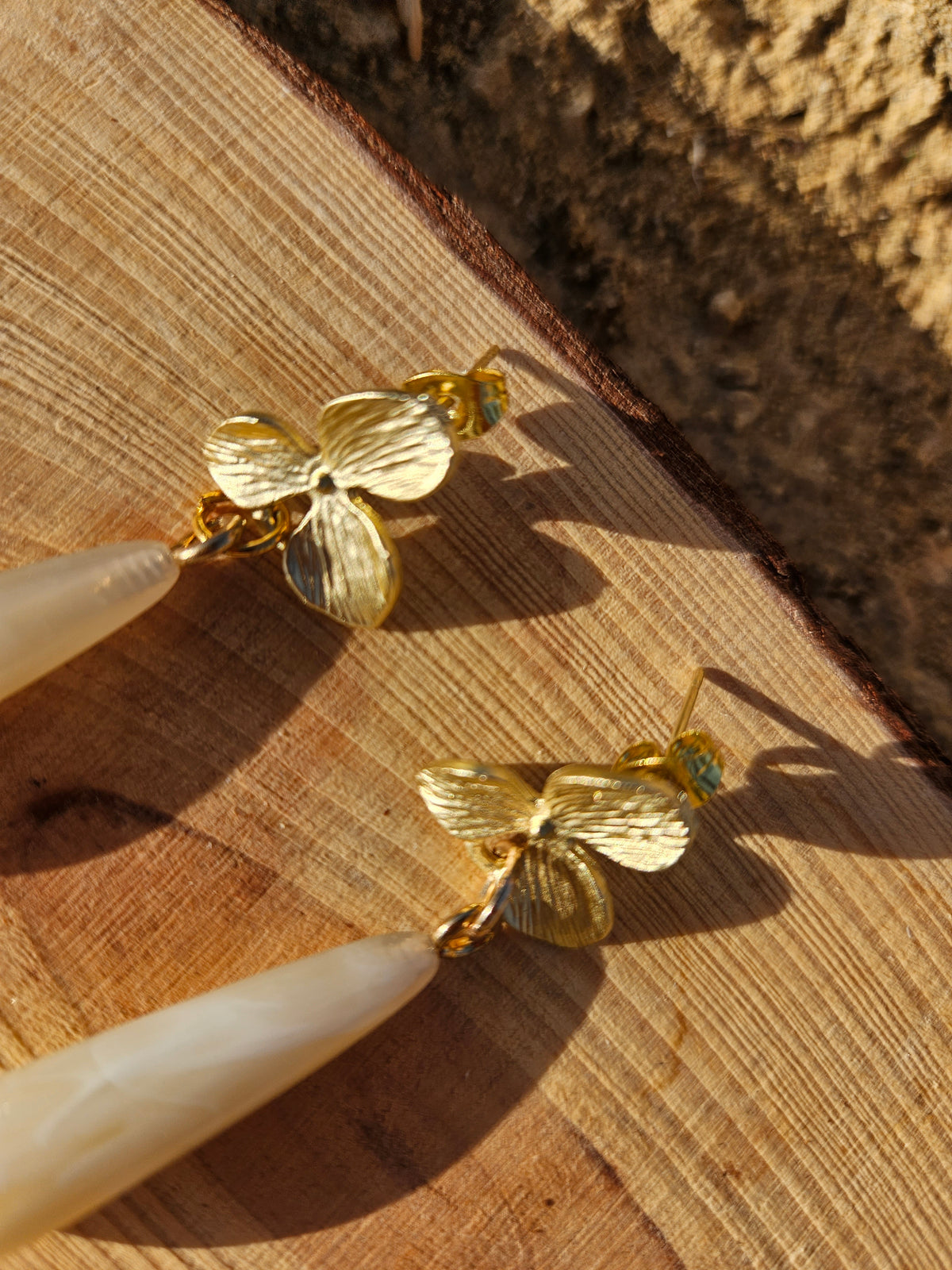 Pendientes dorados con flor y gota marfil, detalle de la flor