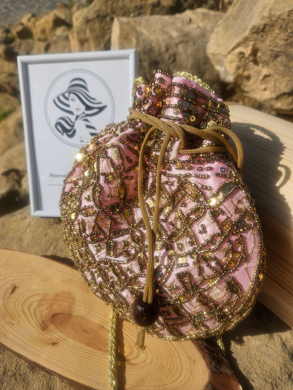 Bolso saco rosa y dorado con lentejuelas, cierre de cordón y detalle superior