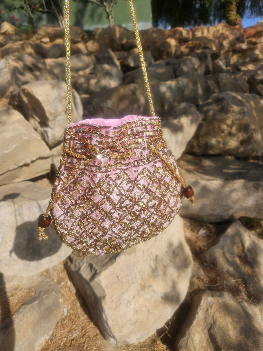 Bolso saco bordado rosa y dorado con cordones dorados y borlas en los laterales