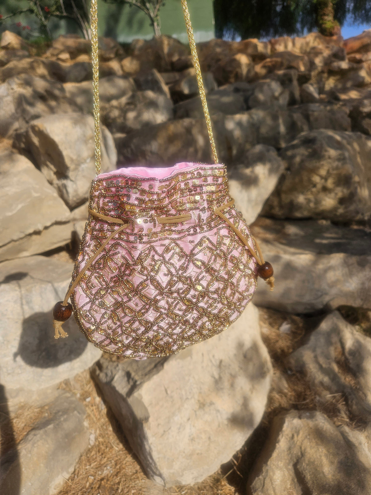 Bolso saco bordado rosa y dorado con cordones dorados y borlas en los laterales