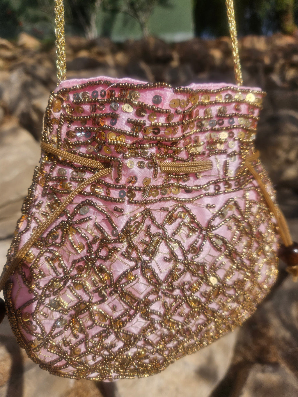 Bolso saco rosa con lentejuelas doradas y bordado geométrico, cierre de cordón
