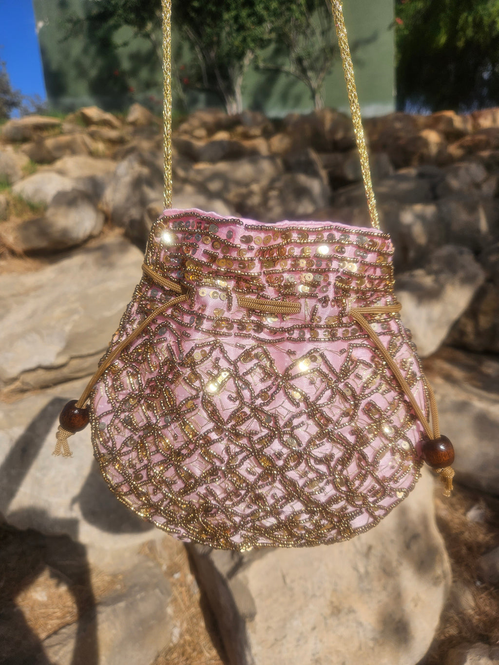 Bolso saco rosa y dorado con bordado fino, cordón de cierre y borlas laterales