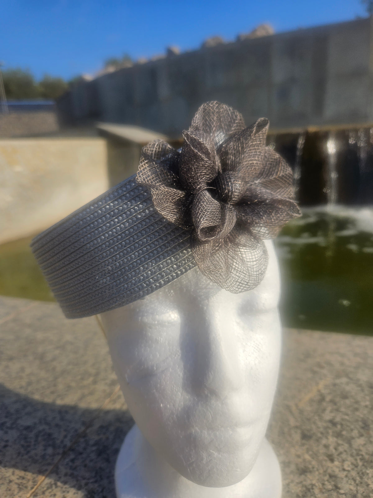 Sombrero casquete gris con ala corta y flor de malla transparente en la copa