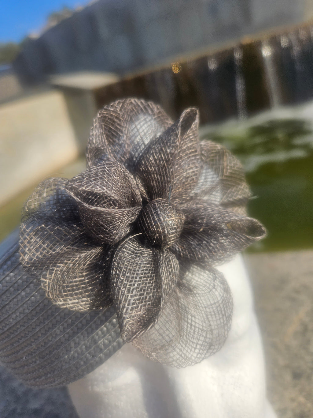 Flor de tul negra decorativa sobre sombrero casquete gris, vista en detalle