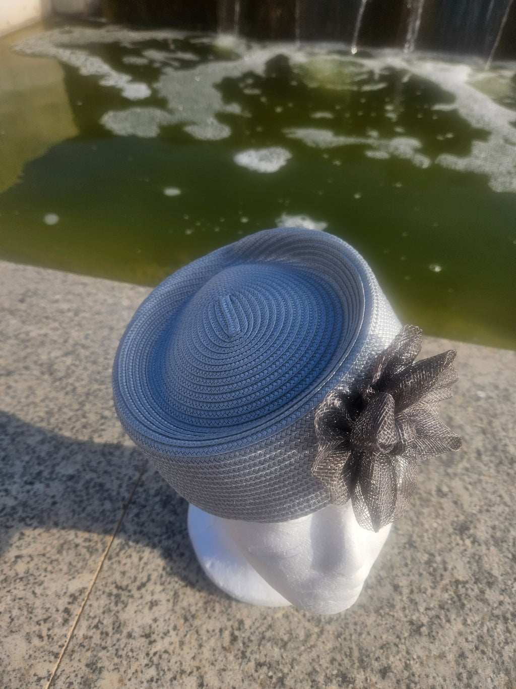 Sombrero casquete azul claro con flor de tul negra en un lateral