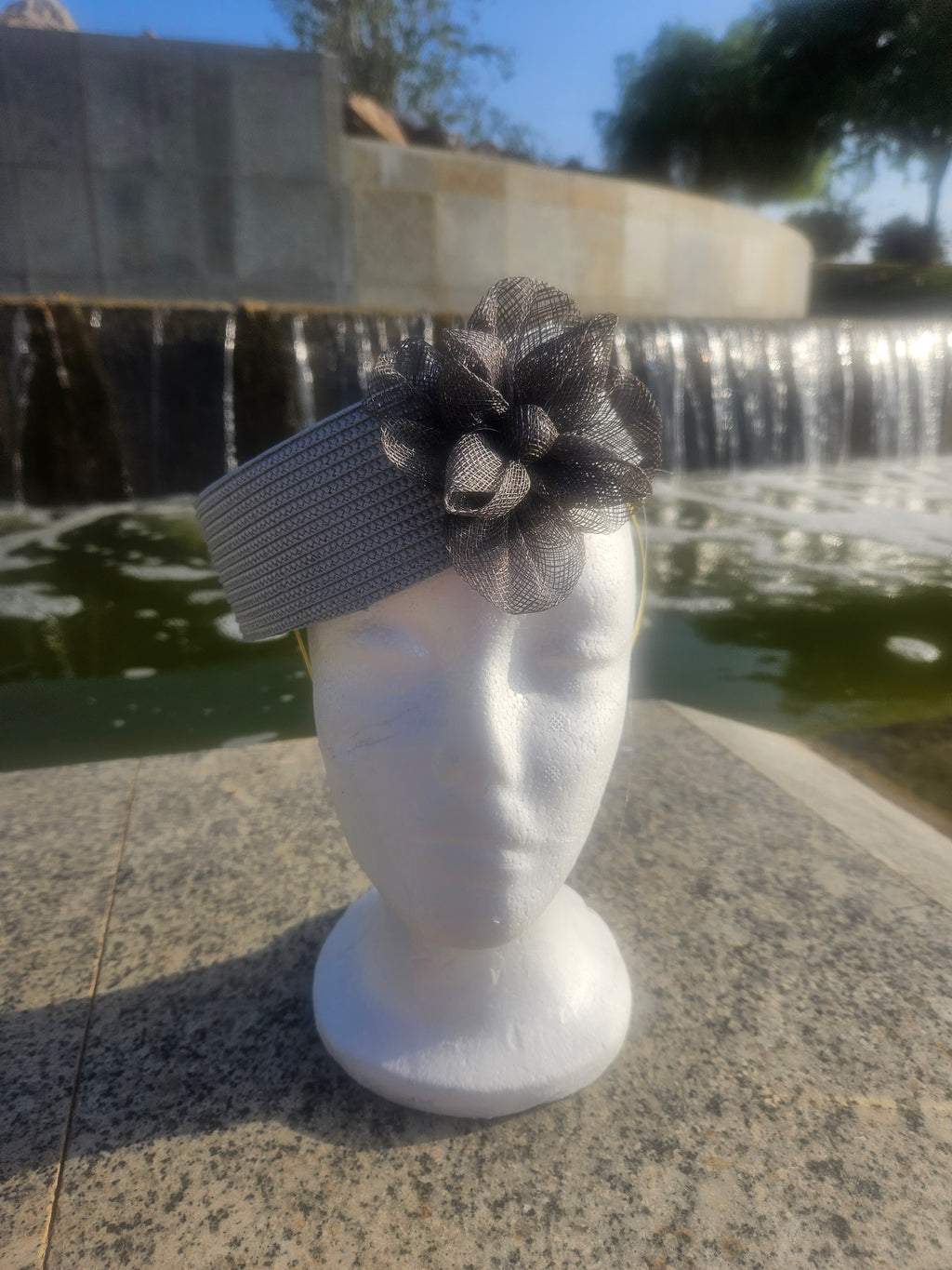 Sombrero casquete gris con flor de tul grande y cinta a rayas en el lateral