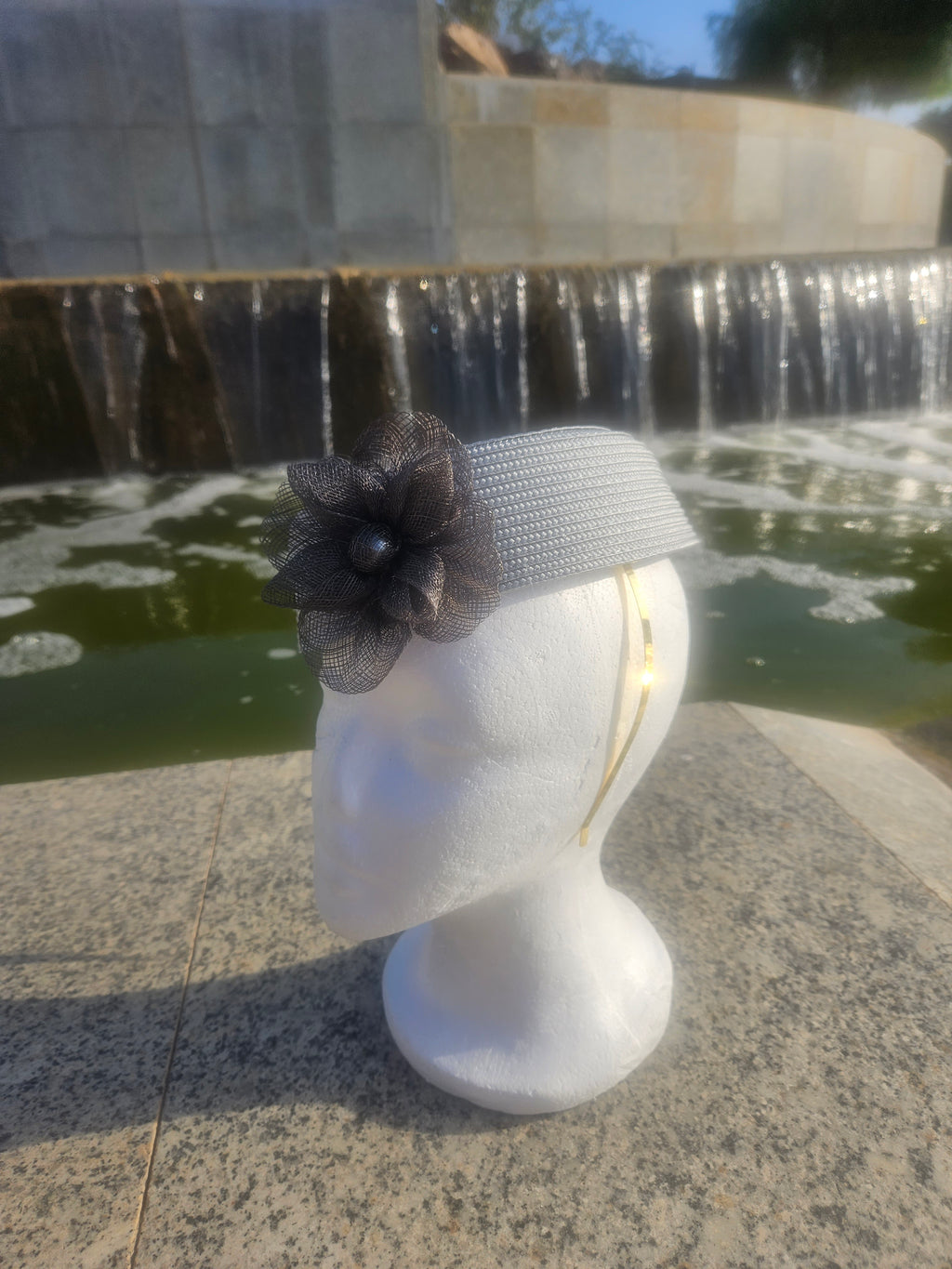 Sombrero casquete gris con flor de tul y etiqueta interior visible en la cinta