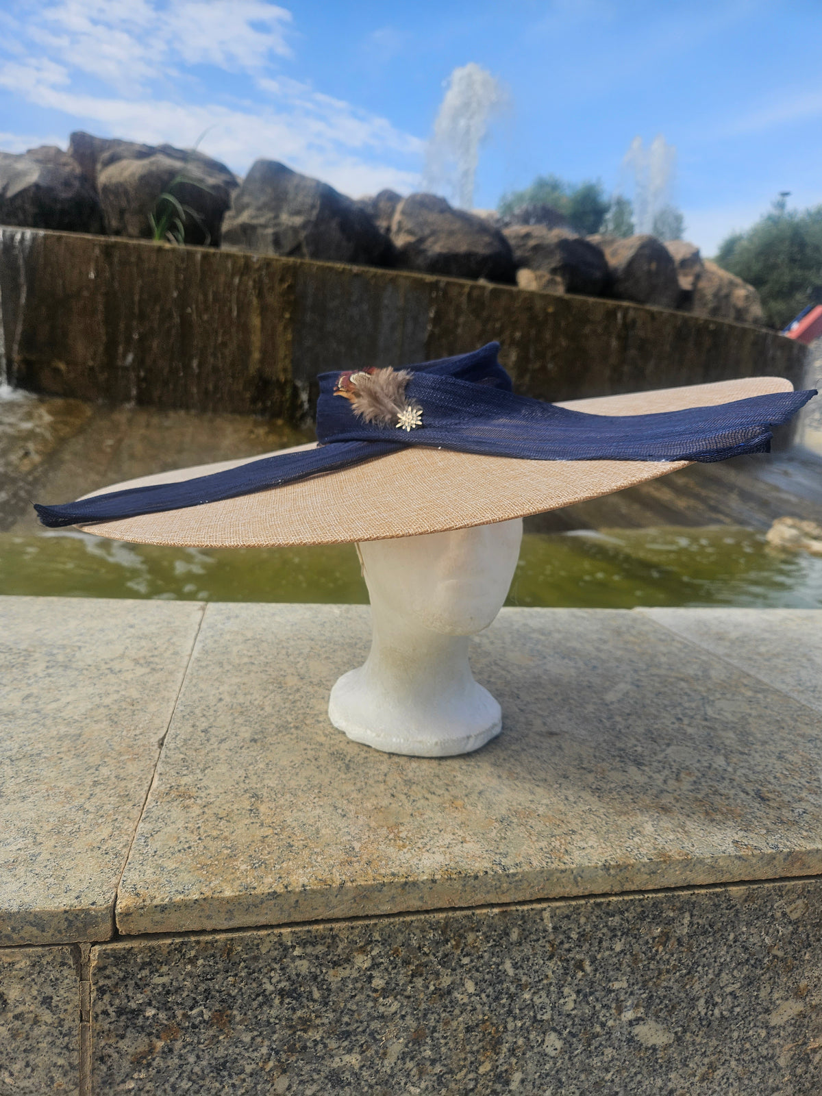 Pamela de ala ancha azul marino con lazo al lado y pluma decorativa