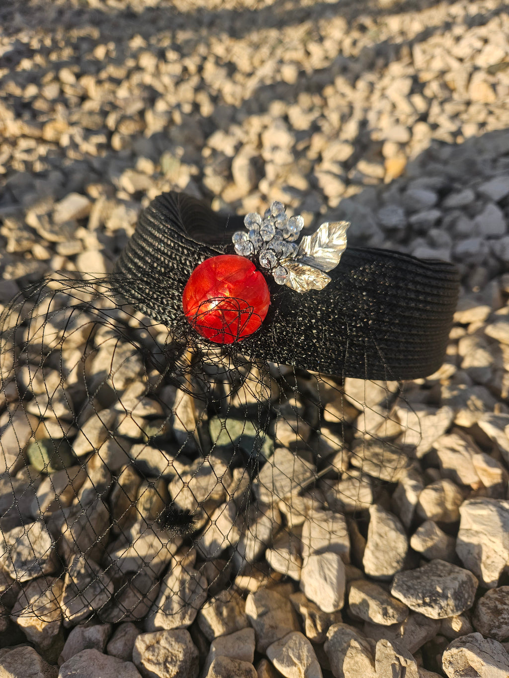 Sombrero casquete negro con adorno rojo y flor plateada, malla frontal