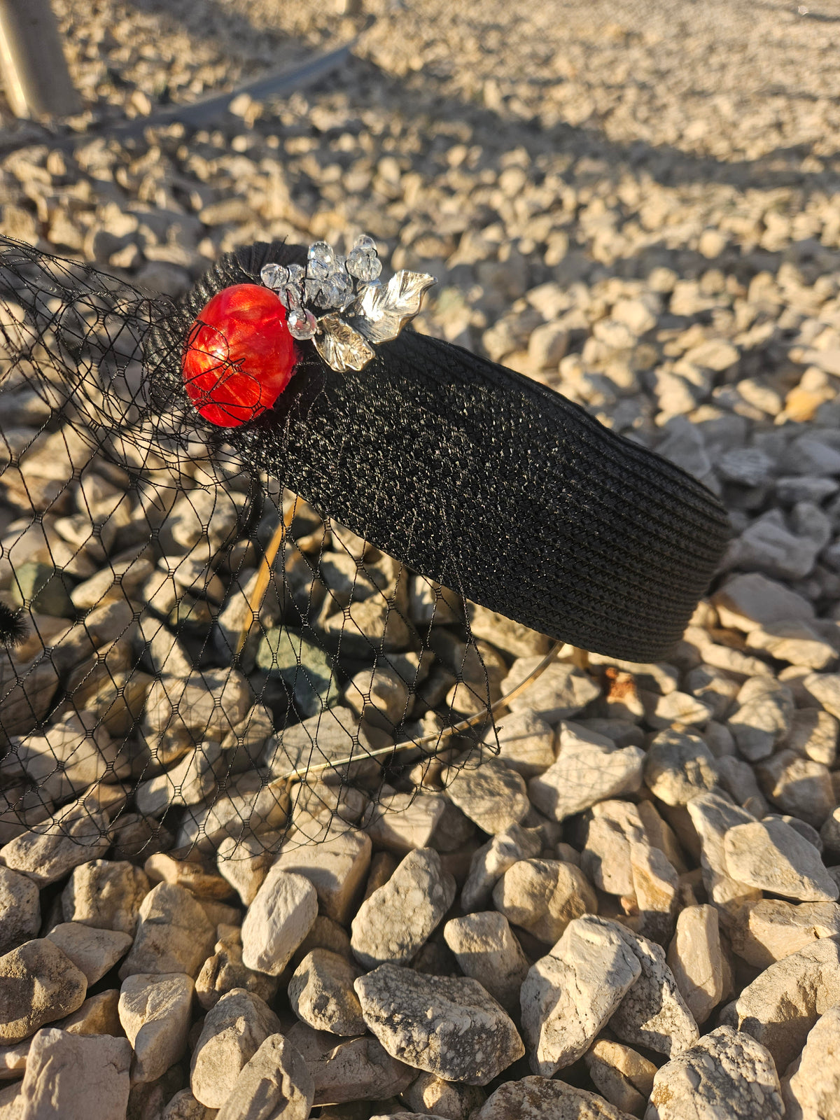 Sombrero casquete negro tejido, adorno rojo y flor plateada, ala corta