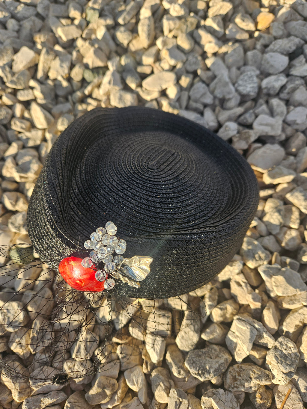 Sombrero casquete negro redondo con adorno rojo y broche flor plateada