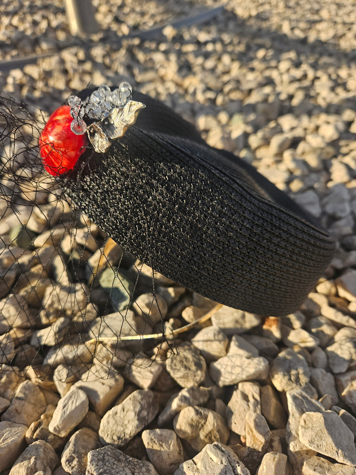 Sombrero casquete negro de ala corta con adorno rojo y flor plateada