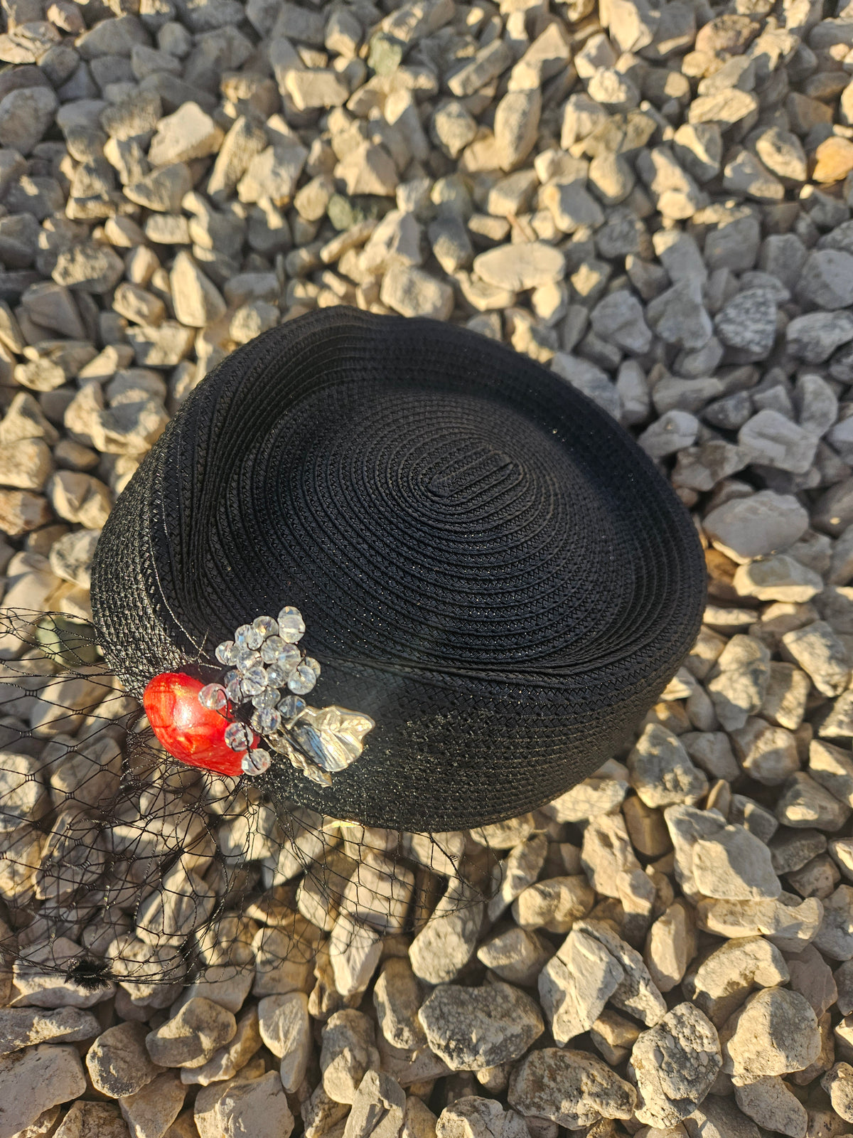 Sombrero casquete negro con adorno rojo y flores plateadas, vista superior