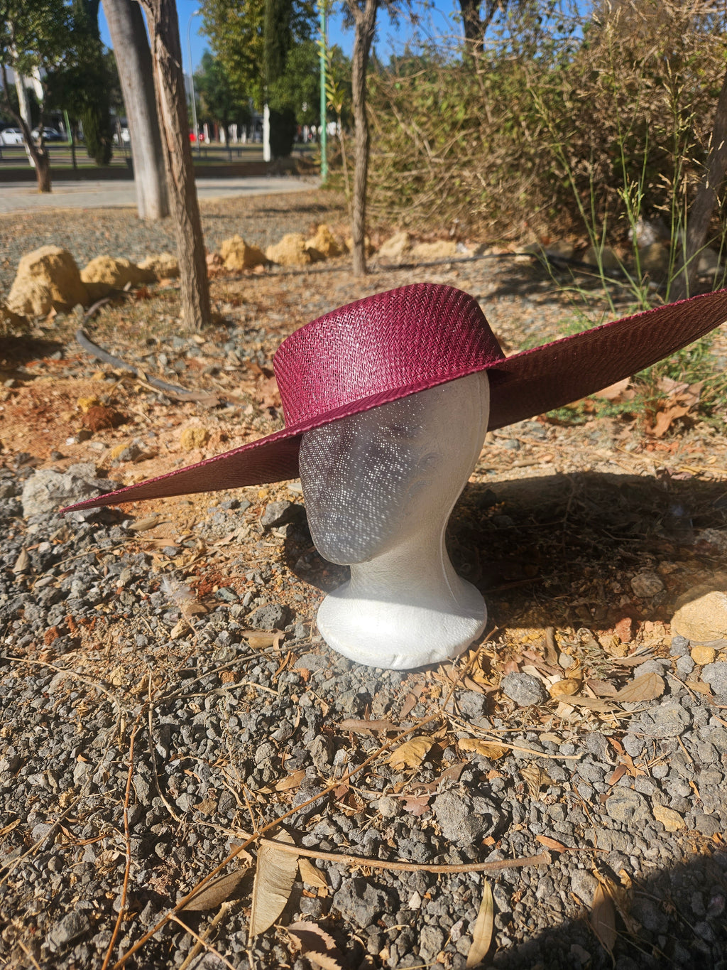 Sombrero burdeos de ala ancha sobre soporte, textura tejida y copa redondeada