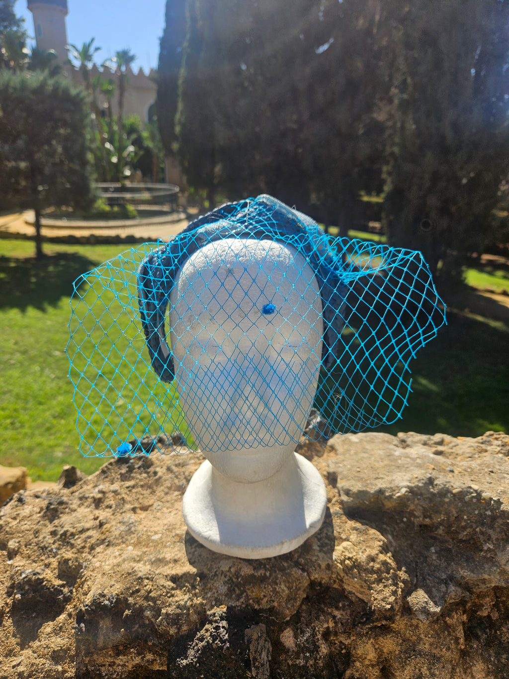 Diadema Águeda azul con velo de malla y forma de turbante sobre un maniquí