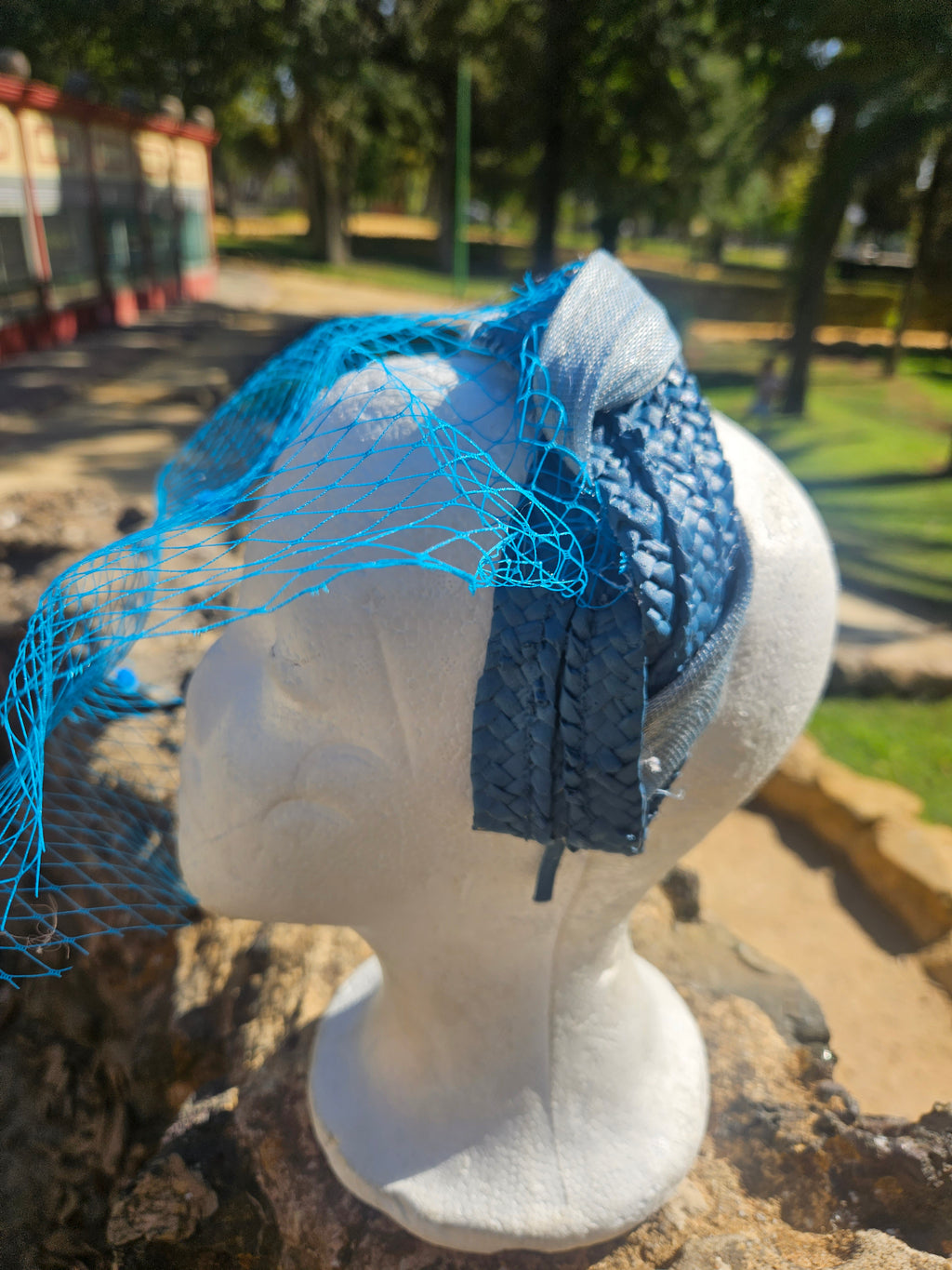 Diadema Águeda azul con velo de malla y moño lateral sobre maniquí