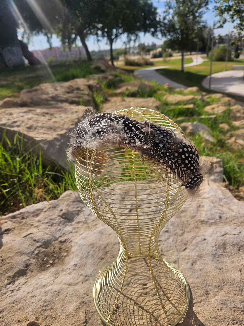 Diadema con base de malla dorada y banda de plumas negras salpicadas