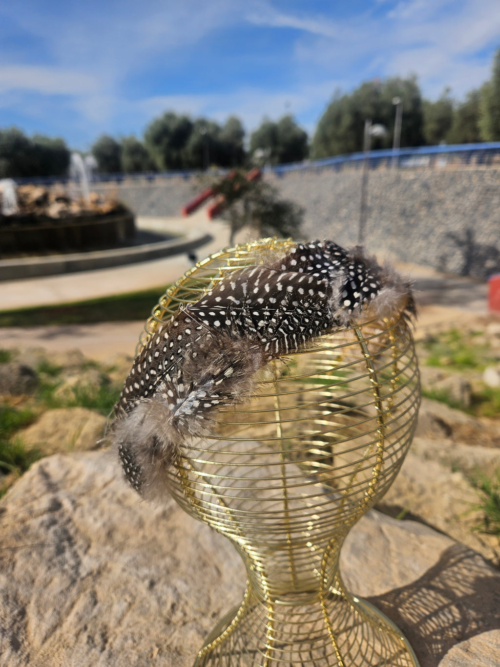 Diadema de malla dorada con banda negra de plumas y adorno tipo pedrería