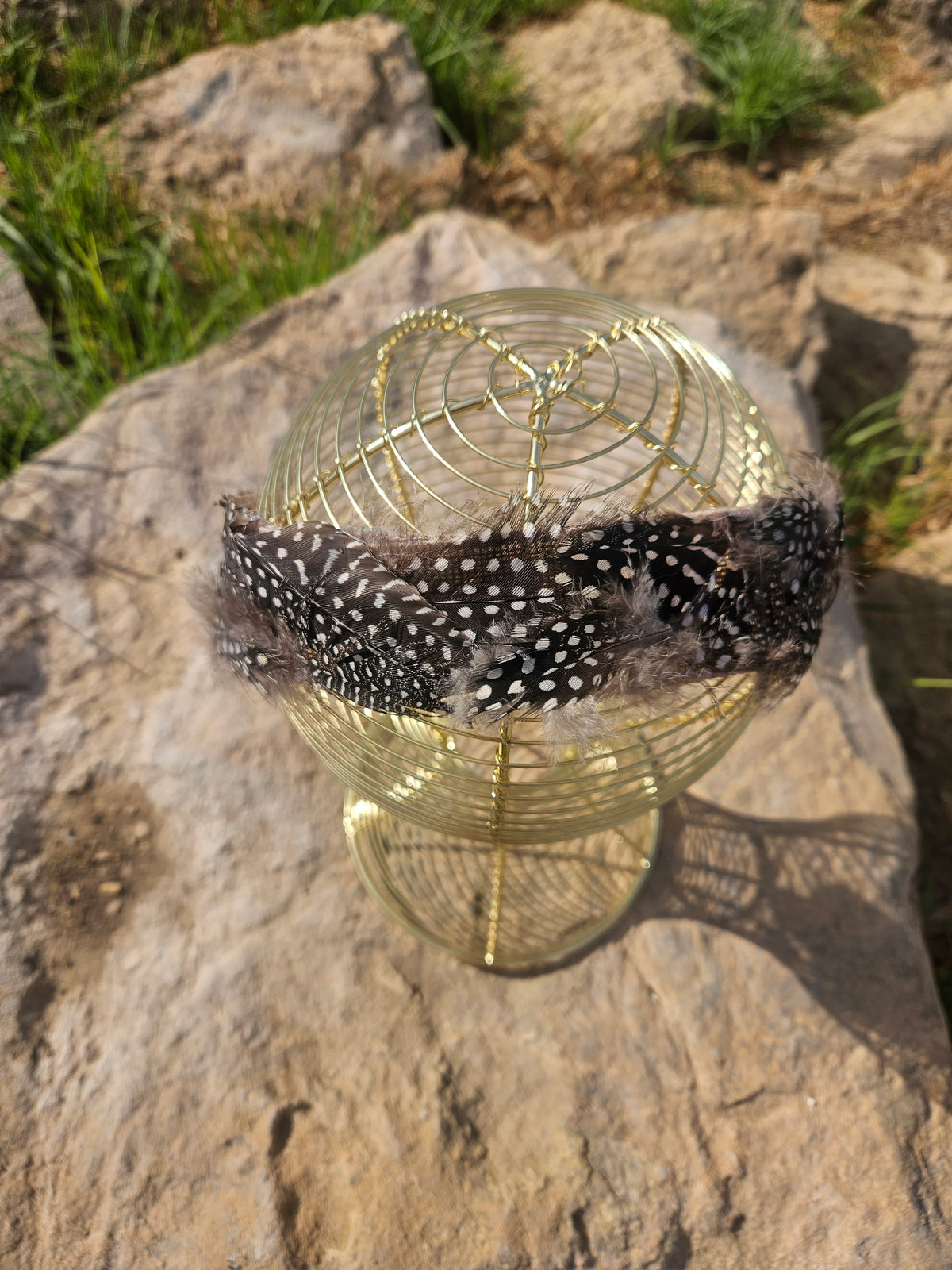 Diadema de malla dorada con banda negra de plumas y lazo de tela marrón