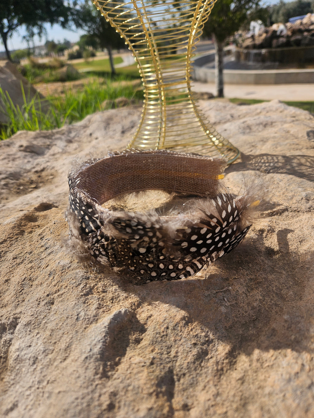 Diadema de malla dorada con banda de plumas negras y forro marrón