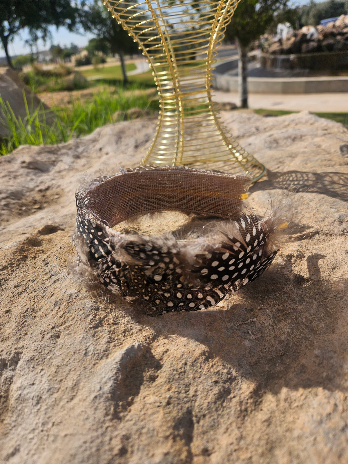 Diadema de malla dorada con banda de plumas negras y forro marrón
