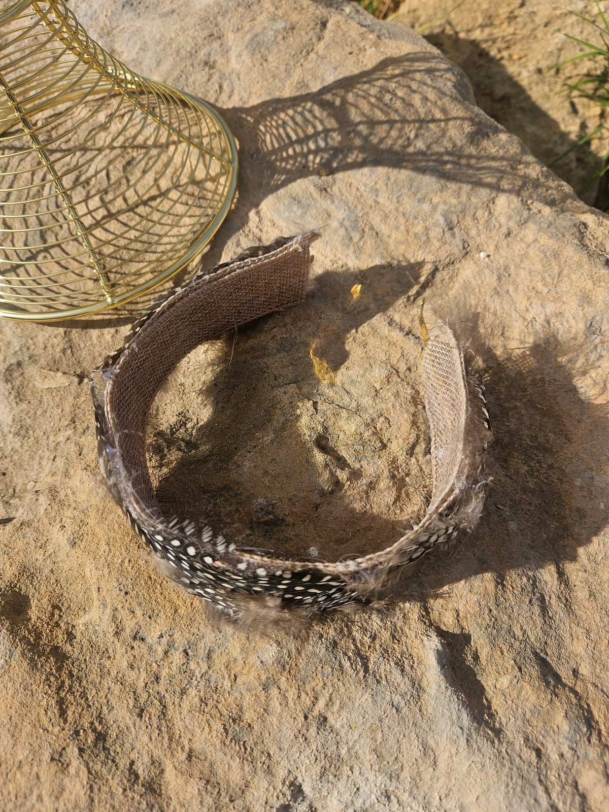 Diadema de malla dorada con anillo de banda negra con plumas blancas