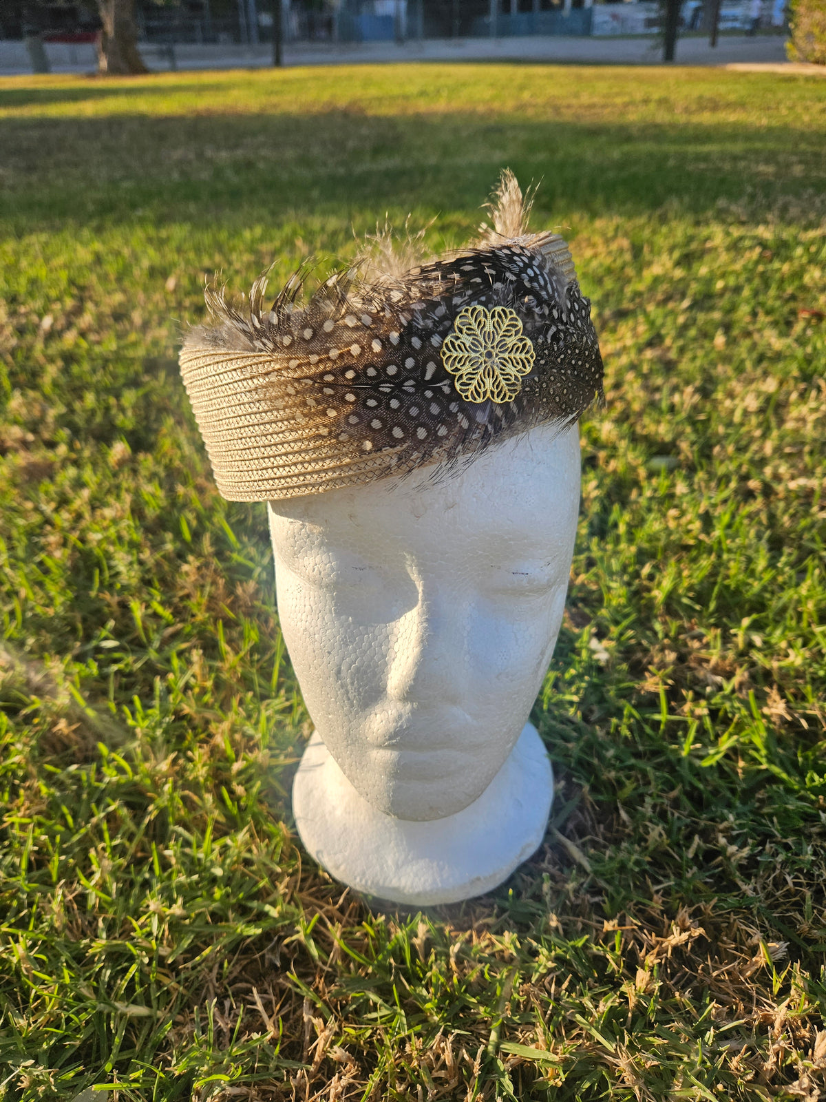 Sombrero casquete beige y negro con malla punteada, plumas y flor amarilla bordada