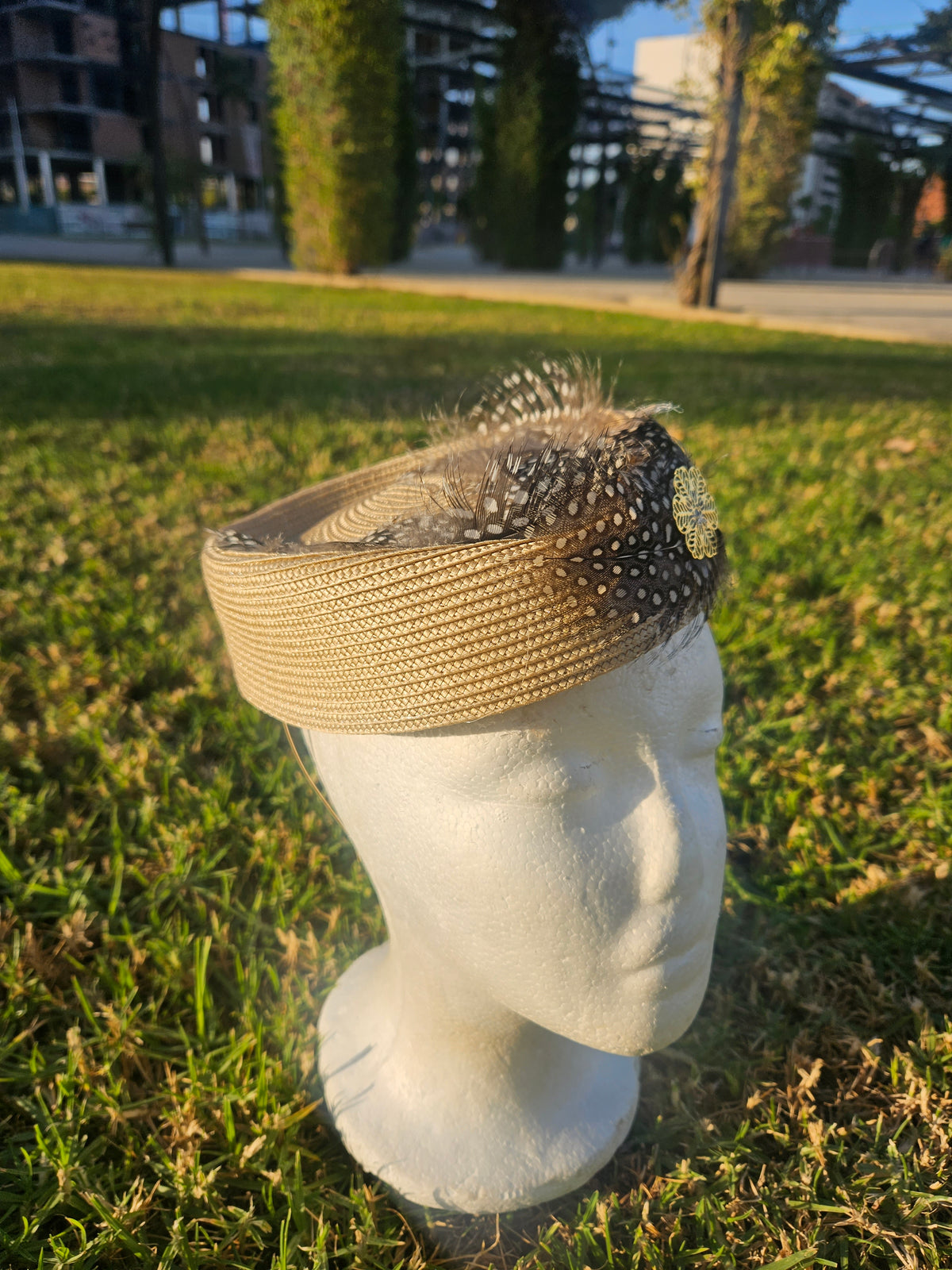Sombrero casquete beige con composición de malla negra punteada y plumas en la copa