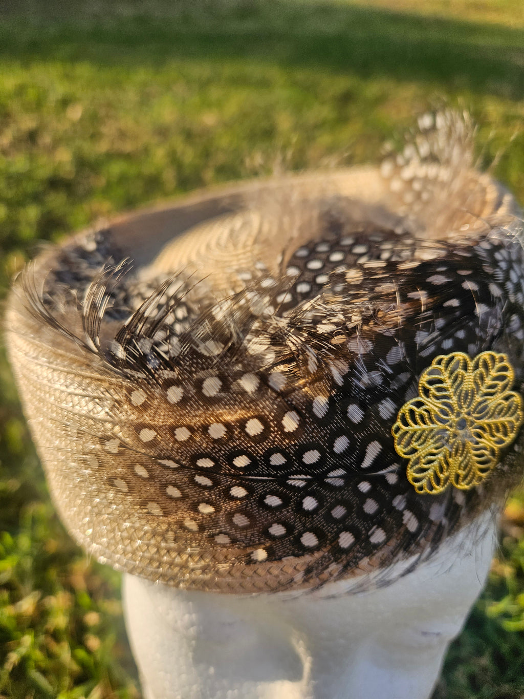 Sombrero casquete con detalle de malla negra punteada, plumas y flor amarilla bordada