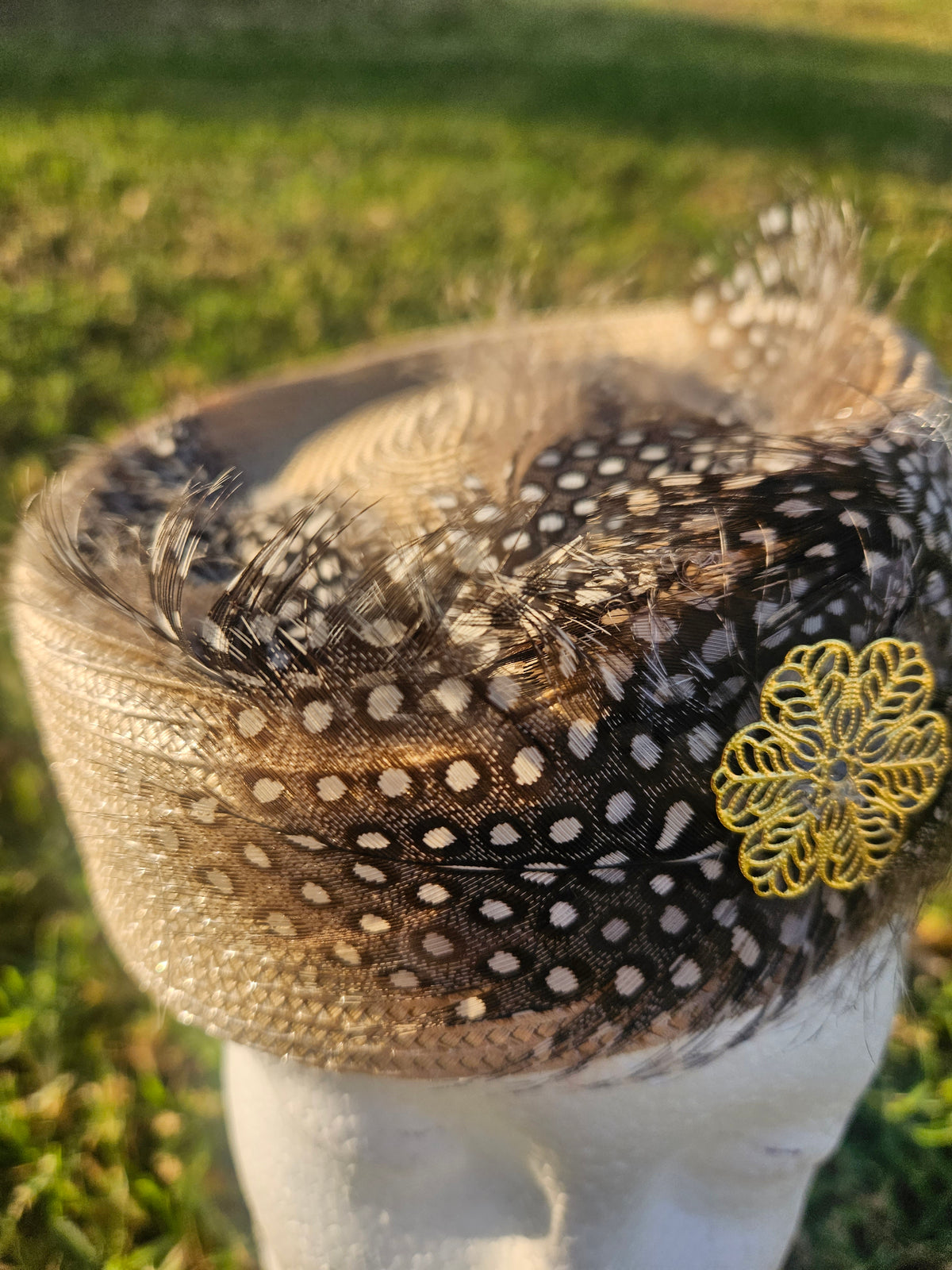 Sombrero casquete con detalle de malla negra punteada, plumas y flor amarilla bordada