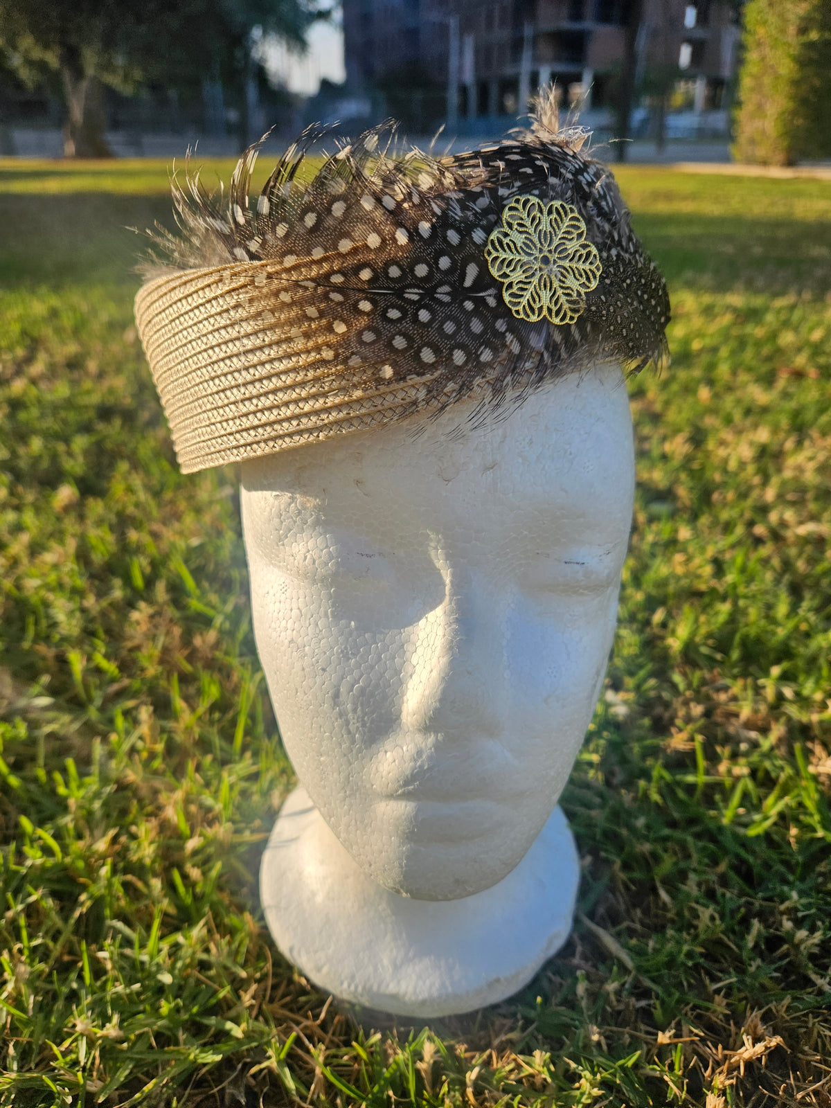 Sombrero casquete beige y negro con plumas arriba y flor amarilla bordada en un lado
