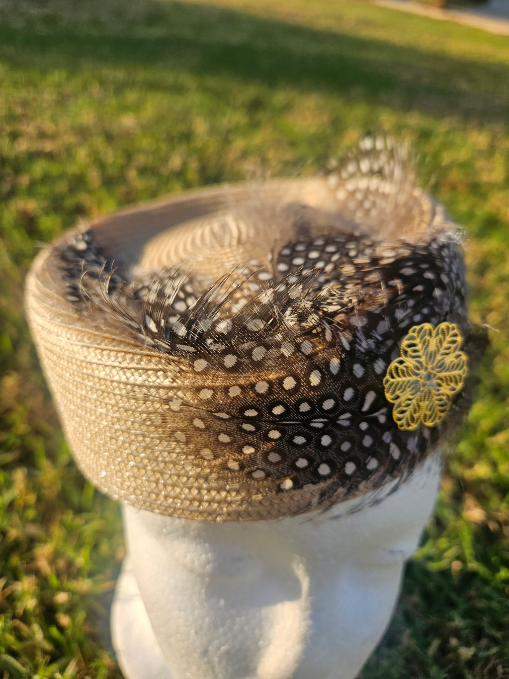 Sombrero casquete con flor amarilla bordada y malla negra punteada sobre base beige