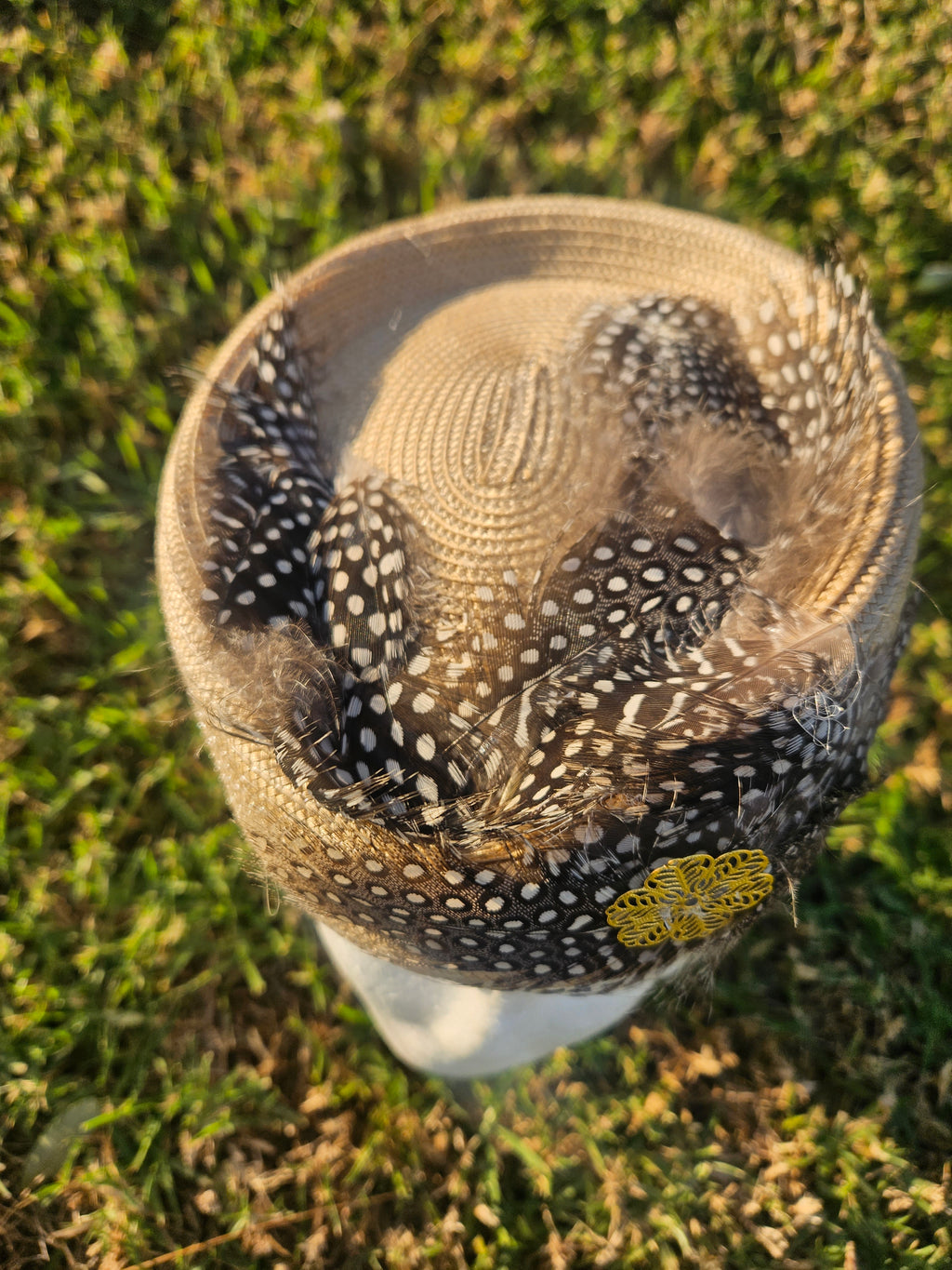 Sombrero casquete beige y negro con malla transparente punteada, plumas y flor amarilla