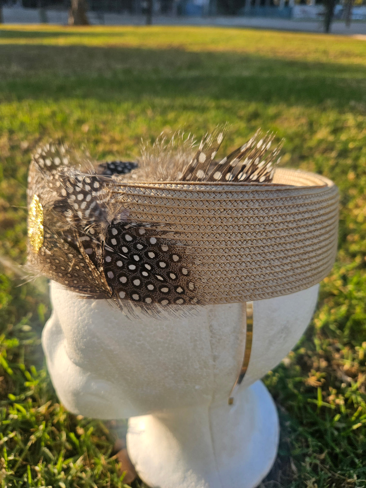 Sombrero casquete beige con malla negra punteada, plumas en la parte superior y bordado